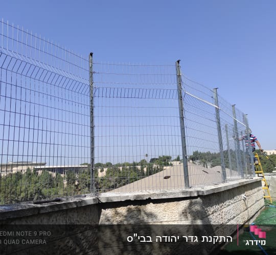 התקנת גדר רשת ממתכת מעל חומת אבן